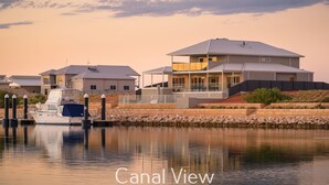 Blick auf einen Kanal mit einem modernen Haus und einem Boot, das an der Anlegestelle liegt.