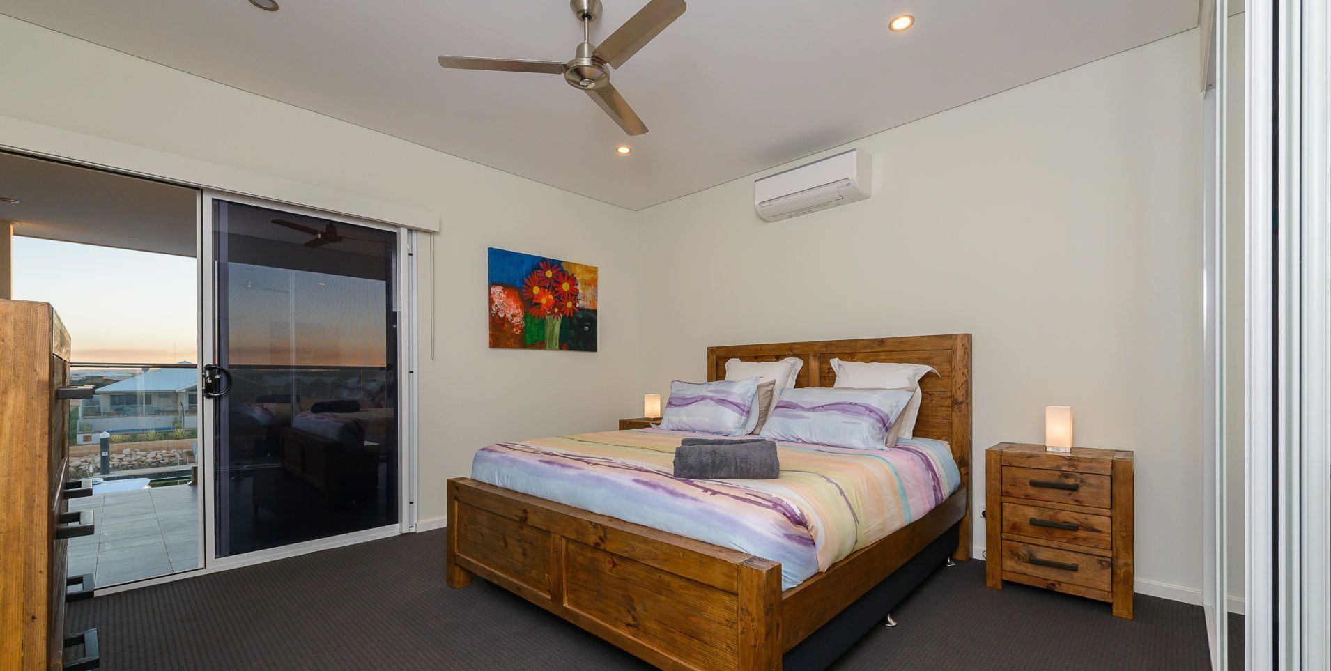 Une chambre à l’étage, dotée d’un lit king-size, d’un ventilateur de plafond, d’un appareil de climatisation et offrant une vue sur l’extérieur grâce à une porte-fenêtre coulissante.
