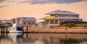 A canal view with a modern house and a boat docked at the pier. - 32 Corella Court - Large Marina property with room for all (EXMOUTH)
