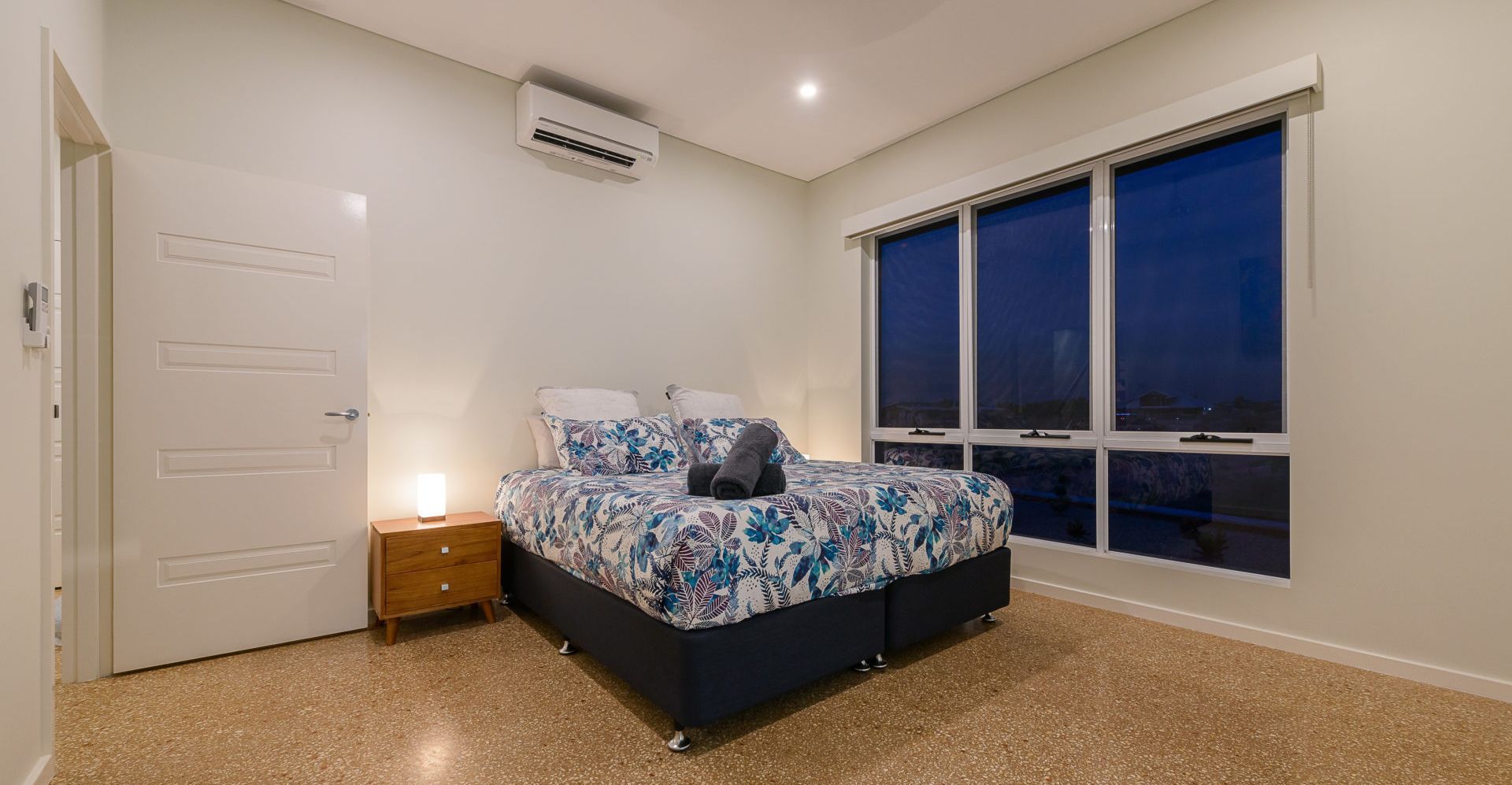 A bedroom with a bed, bedside table, and a window with a view.