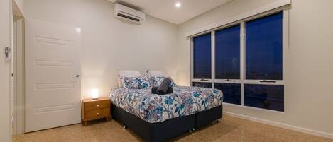 A bedroom with a bed, bedside table, and a window with a view.