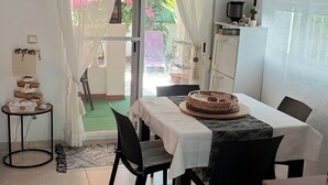 Un'area pranzo con un tavolo apparecchiato per quattro persone, un tavolino rotondo con una torta, e un armadietto con uno specchio.