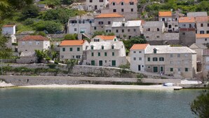 A coastal village with stone buildings, a sandy beach, and a calm sea.