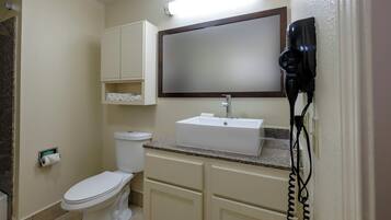 Un baño con inodoro, lavabo, espejo y secador de pelo.