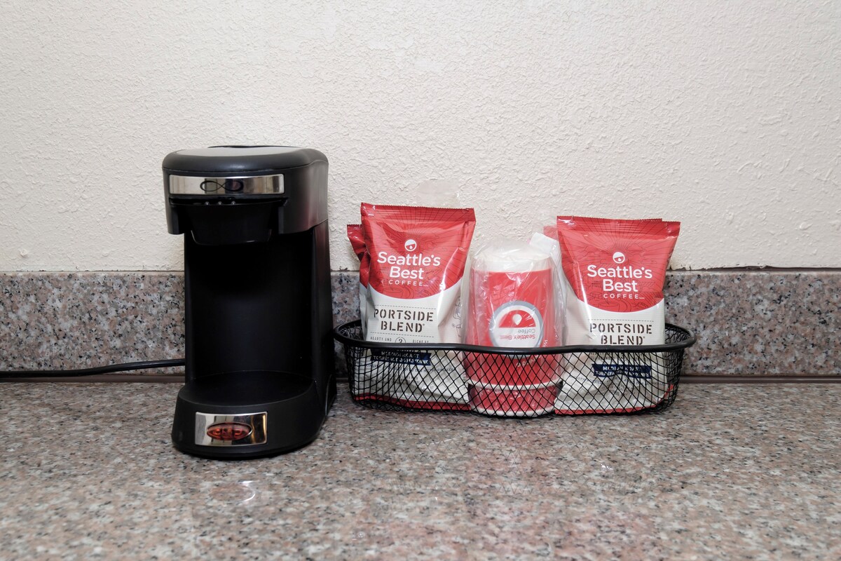 A coffee maker and two bags of Seattle's Best coffee on a kitchen counter.