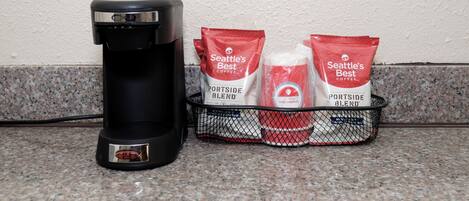 A coffee maker and two bags of Seattle's Best coffee on a kitchen counter.