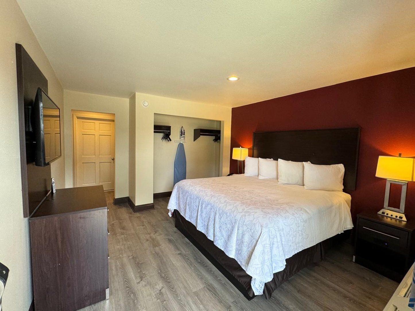 A hotel room with a large bed, a TV, a desk, and a wardrobe.