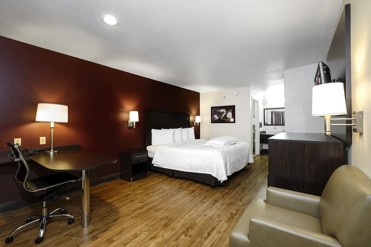 A hotel room with a bed, desk, chair, and bedside lamps.