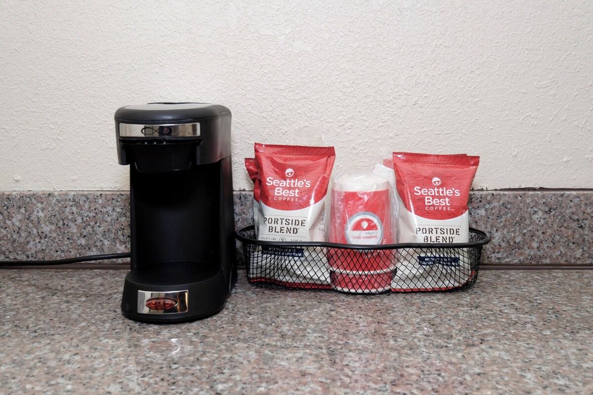 A coffee maker and two bags of Seattle's Best coffee on a kitchen counter.