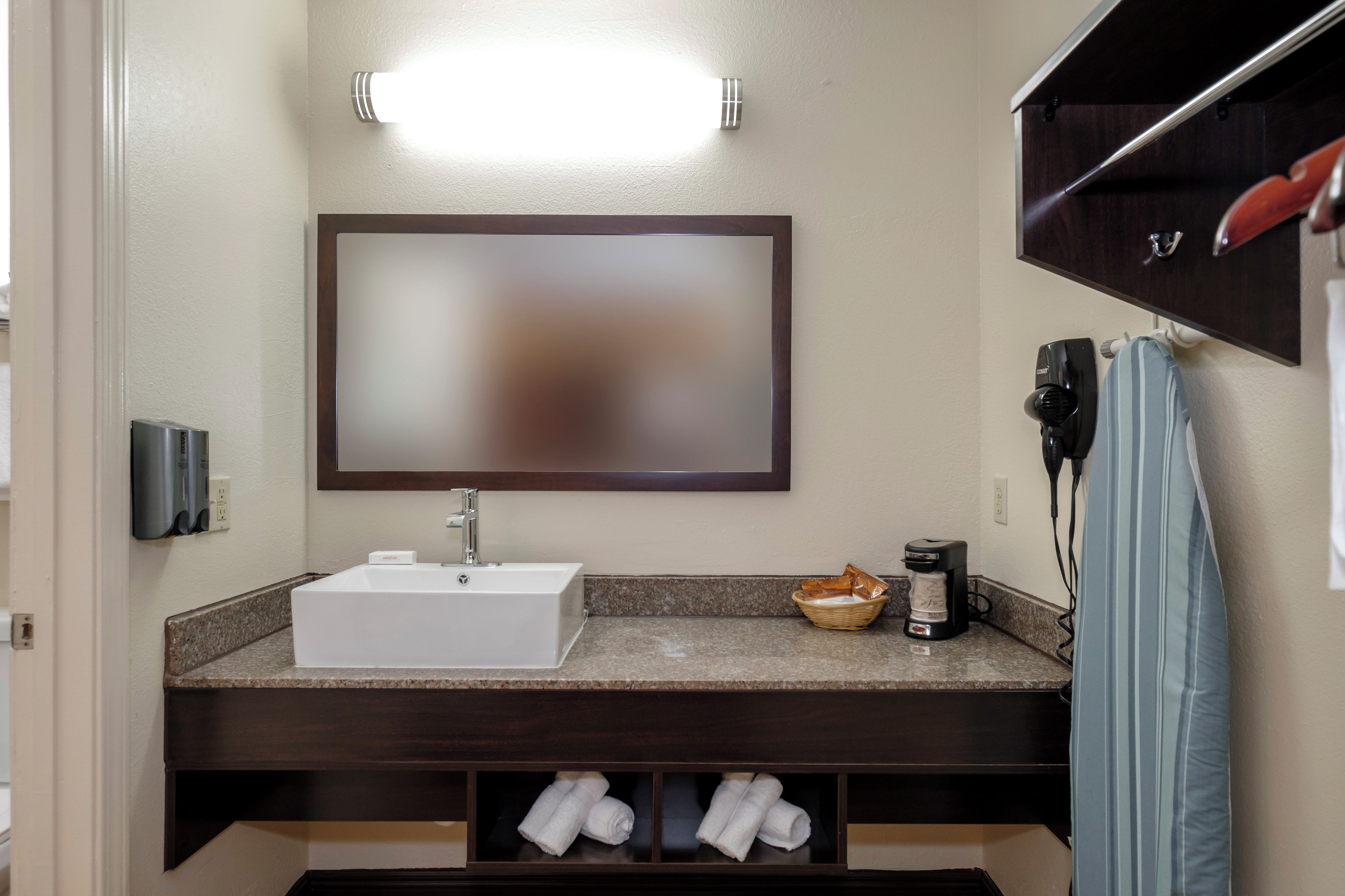 Une salle de bain avec un lavabo blanc, un miroir, un porte-serviettes et une étagère pour ranger les serviettes.