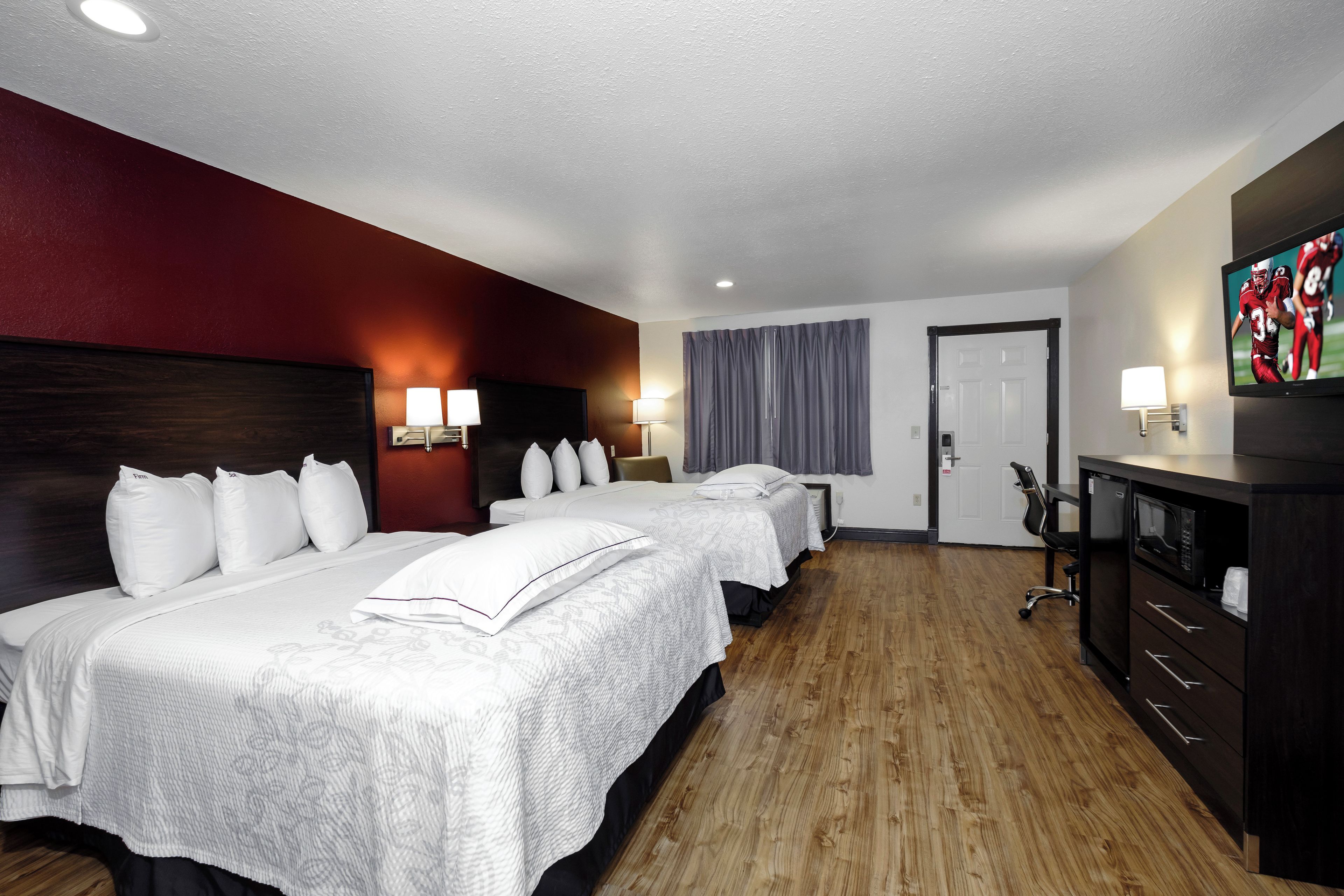 Ein Hotelzimmer mit zwei Betten, einem Fernseher, einem Schreibtisch mit Stuhl und einem Kleiderschrank.