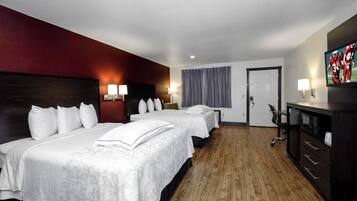 Ein Hotelzimmer mit zwei Betten, einem Fernseher, einem Schreibtisch mit Stuhl und einem Kleiderschrank.