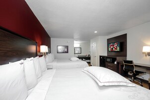 A hotel room with two beds, a desk, a television, and a mirror.