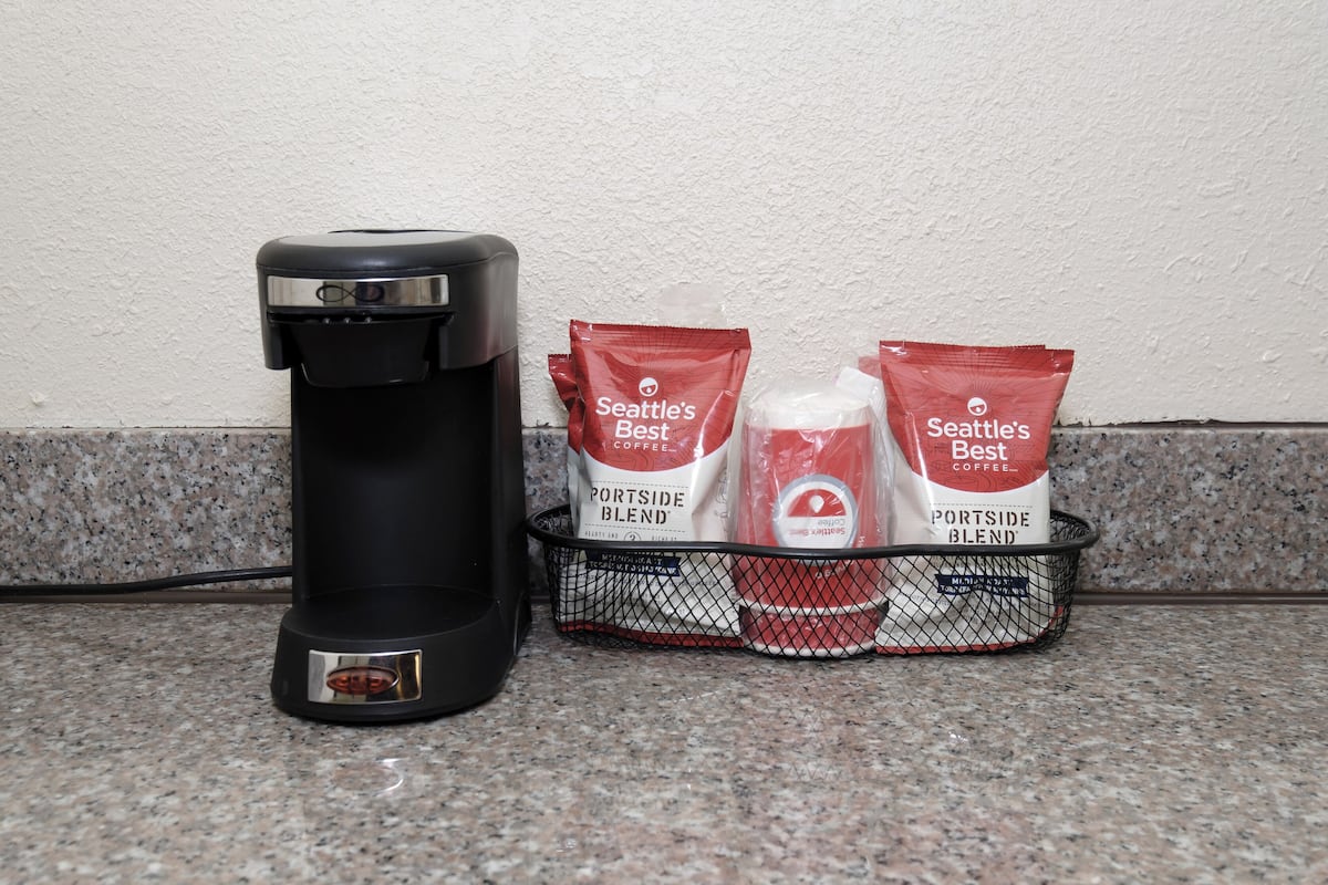 A coffee maker and two packets of Seattle's Best coffee on a granite countertop.