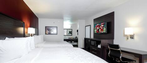 A hotel room with two beds, a desk, a chair, a television, and a bathroom.