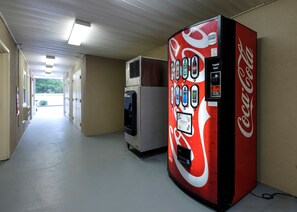 A hallway with vending machines, including a Coca-Cola machine, and a refrigerator. - Red Roof Inn PLUS+ Hammond (Hammond)