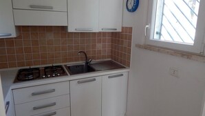 Uma cozinha com armários brancos, fogão a gás, pia e janela com vista.