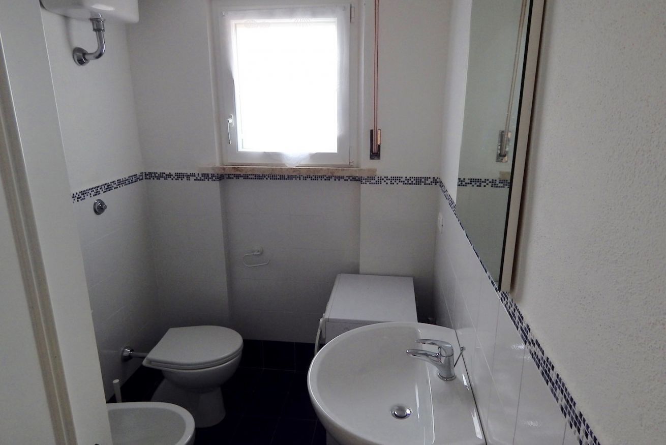 A small bathroom with a toilet, sink, and a window.