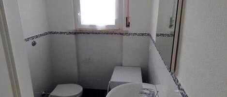 A small bathroom with a toilet, sink, and a window.
