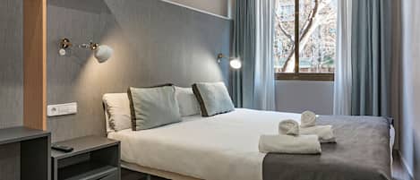 A modern hotel room with a bed, bedside tables, a TV stand, and a window with curtains.