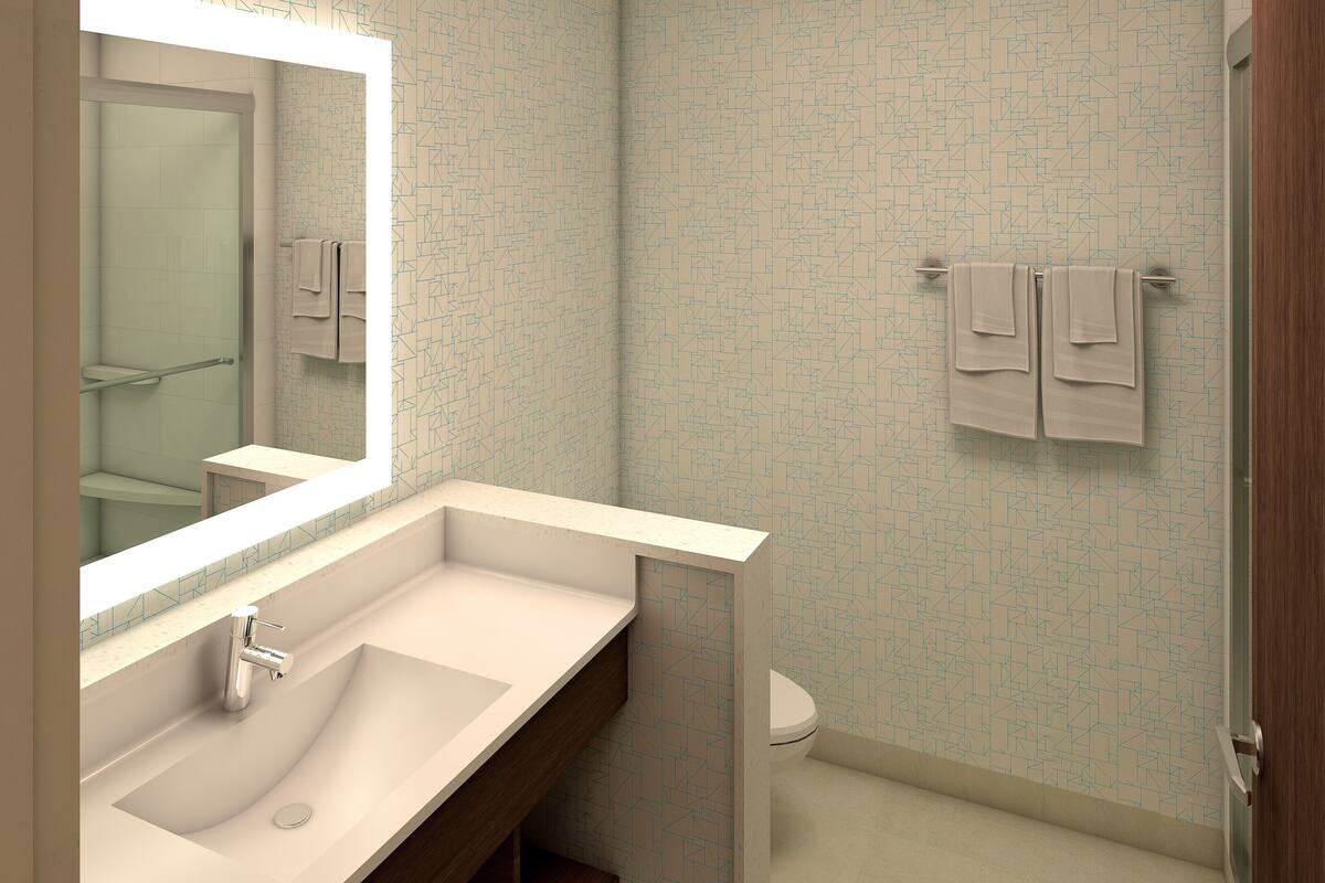 A modern bathroom with a large mirror, a sink, and a toilet.