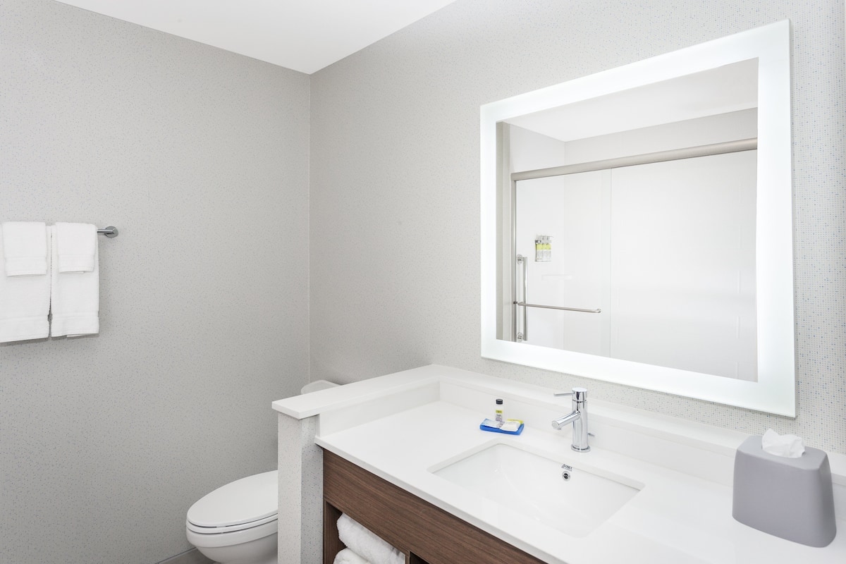 A modern bathroom with a white sink, a large mirror, and a toilet.