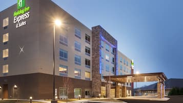 A Holiday Inn Express & Suites building with a modern design, featuring a prominent entrance and a parking area.