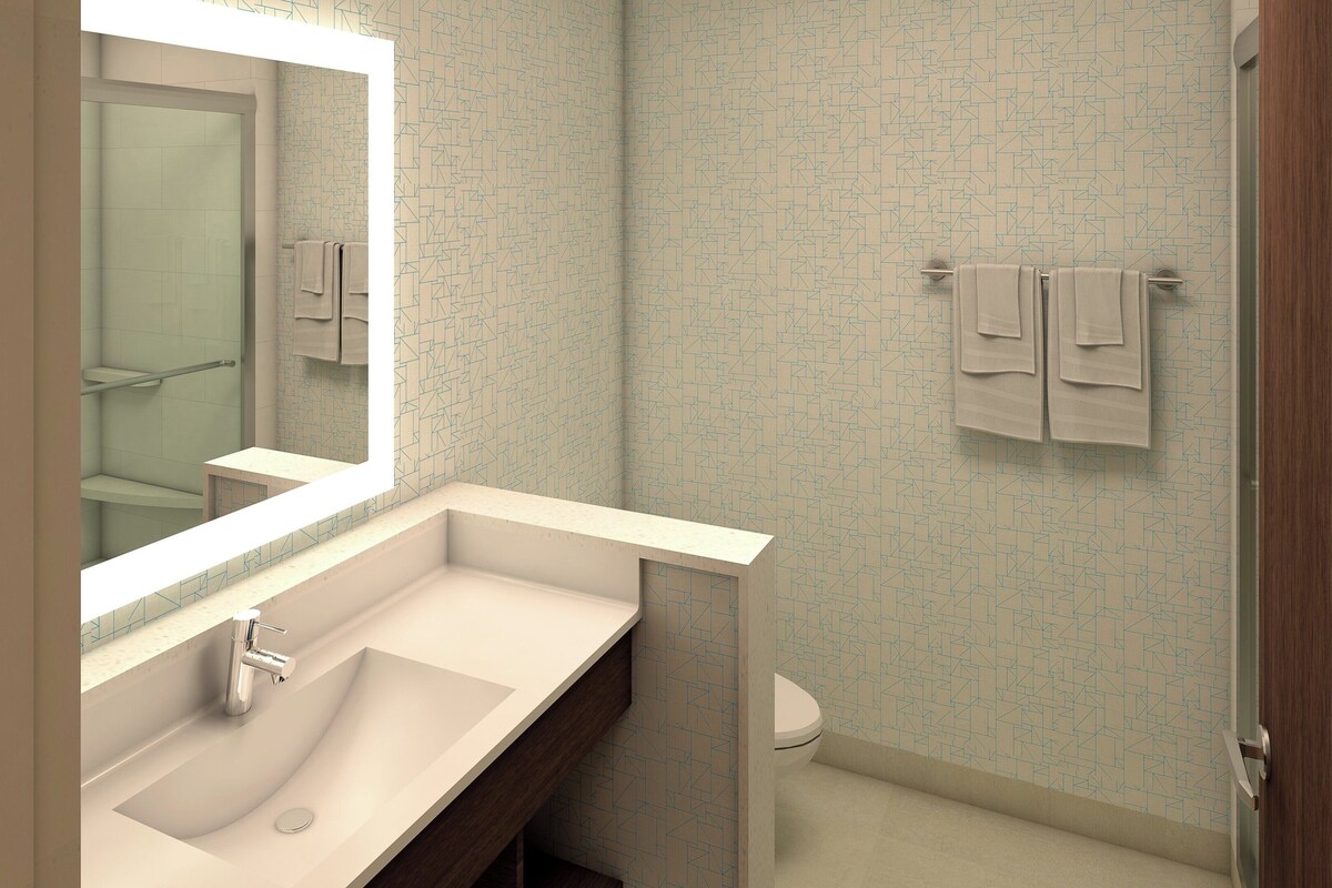 A modern bathroom with a large mirror, a sink, and a toilet.