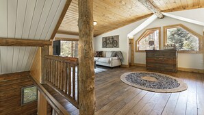 Quarto amplo no estilo loft, com vigas de madeira, uma janela grande, uma obra de arte de bicicleta e um tapete redondo.