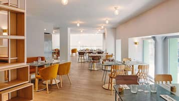 Ein großzügiges Restaurant mit hohen Decken, Holzböden und modernen Sitzmöglichkeiten.