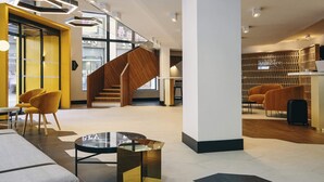 A modern hotel lobby with a wooden staircase, seating areas, and a reception desk. - Hôtel Mercure Marseille Canebière Vieux-Port (Marseille)