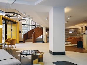 A modern hotel lobby with a wooden staircase, seating areas, and a reception desk. - Hôtel Mercure Marseille Canebière Vieux-Port (Marseille)