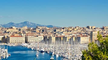 Un port de plaisance rempli de bateaux, un paysage urbain avec des bâtiments historiques et des montagnes en arrière-plan.
