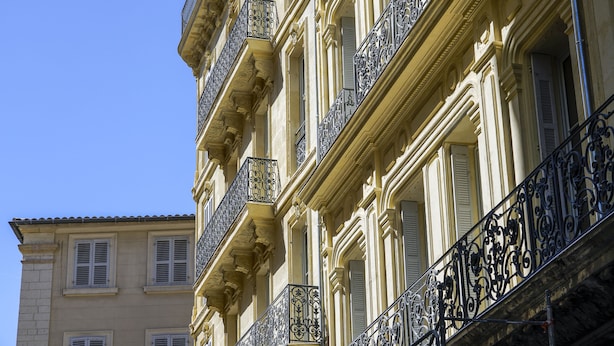 Un edificio de varios pisos con balcones y contraventanas ornamentales.