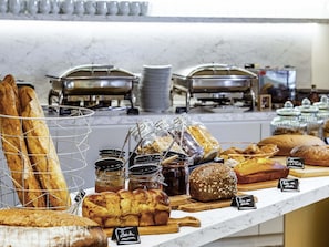 A bakery display with various breads and pastries, including baguettes, croissants, and a loaf of bread with a label.