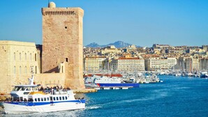 A historic tower by a waterfront with a cityscape in the background. - Hôtel Mercure Marseille Canebière Vieux-Port (Marseille)