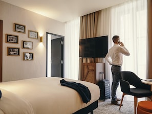 Hotellihuone, jossa on sänky, televisio, työpöytä ja tuoli.