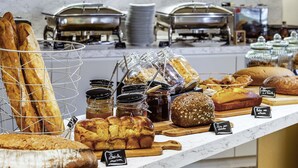 A bakery display with various breads and pastries, including baguettes, croissants, and a loaf of bread with a label.