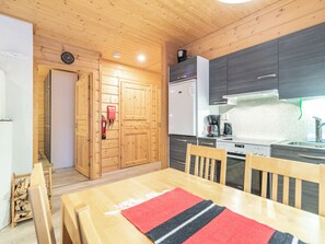 A compact kitchen with wooden cabinets, a refrigerator, a coffee maker, and a stove.