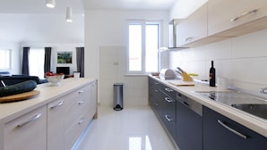 A modern kitchen with light-colored cabinets, a stainless steel sink, and a window providing natural light. - Villa Župa (Imotski)
