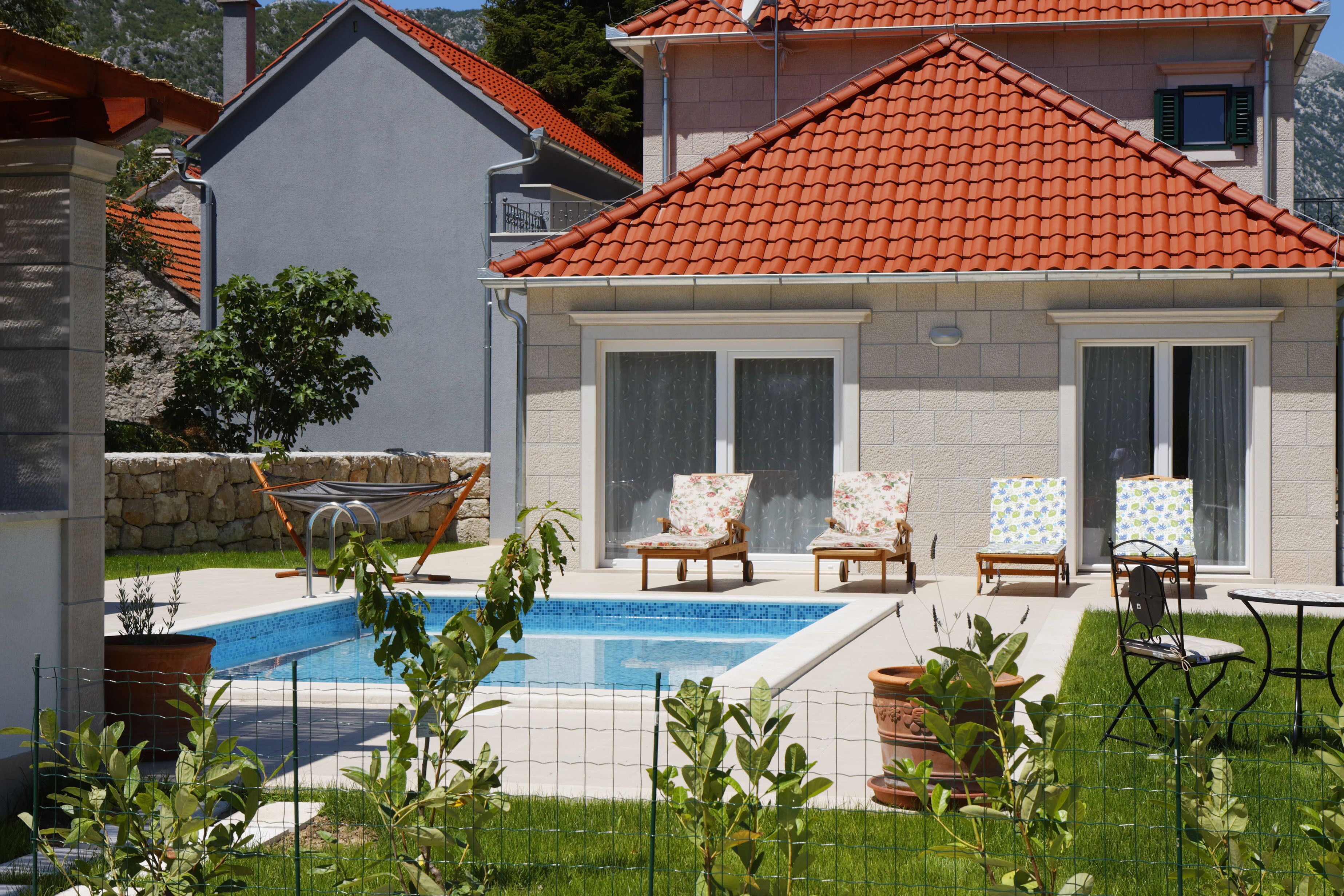 A house with a swimming pool, outdoor seating, and a stone wall.