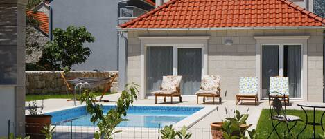 A house with a swimming pool, outdoor seating, and a stone wall.