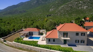 A villa with a swimming pool, stone walls, and a mountainous backdrop. - Villa Župa (Imotski)