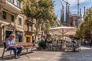 Ein Platz mit Außenbestuhlung, Bänken und Sonnenschirmen.