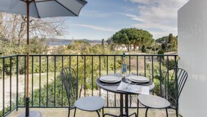 Un balcón con mesa y sillas, una sombrilla y vistas del paisaje.