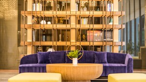 A modern library with a purple sofa, yellow ottomans, and a wooden coffee table. - Mercure Xian Hi Tech Zone (Xi'an)
