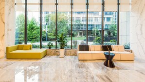 A modern lobby with two sofas, a coffee table, and large windows overlooking a courtyard. - Mercure Xian Hi Tech Zone (Xi'an)