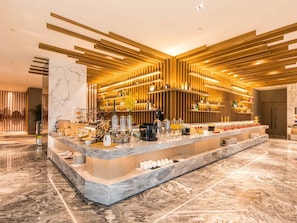 Zona de bar moderna con encimera de mármol, paneles de madera y diverso equipamiento de bar.