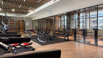 Un gimnasio con equipo de ejercicio, un espejo grande en la pared y techo de madera.