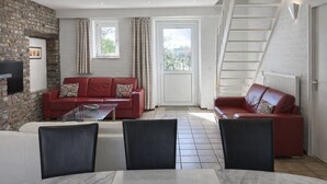 A living room with a red sofa, a glass coffee table, and a staircase leading to an upper floor.